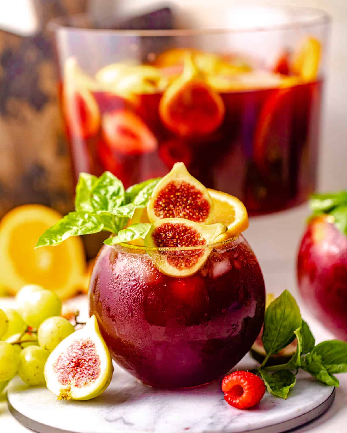 a glass of bourbon sangria in front of a pitcher of wine.