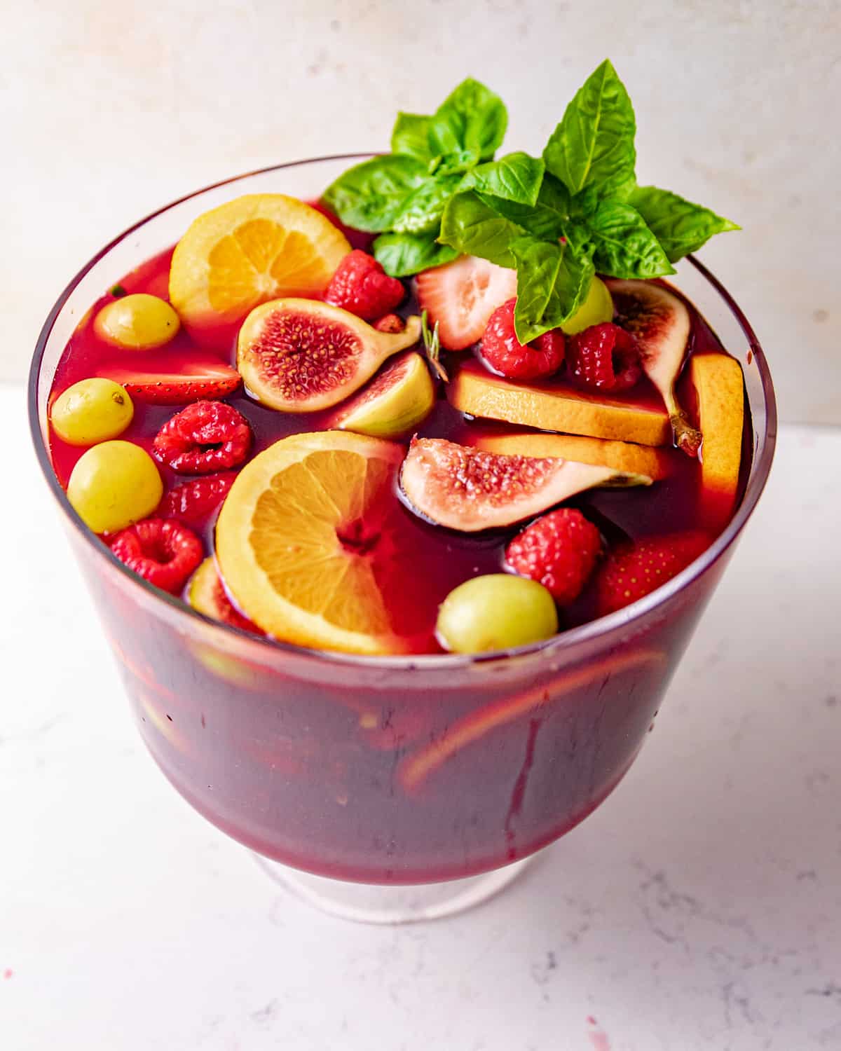 a large pitcher of sangria garnished with fresh basil.