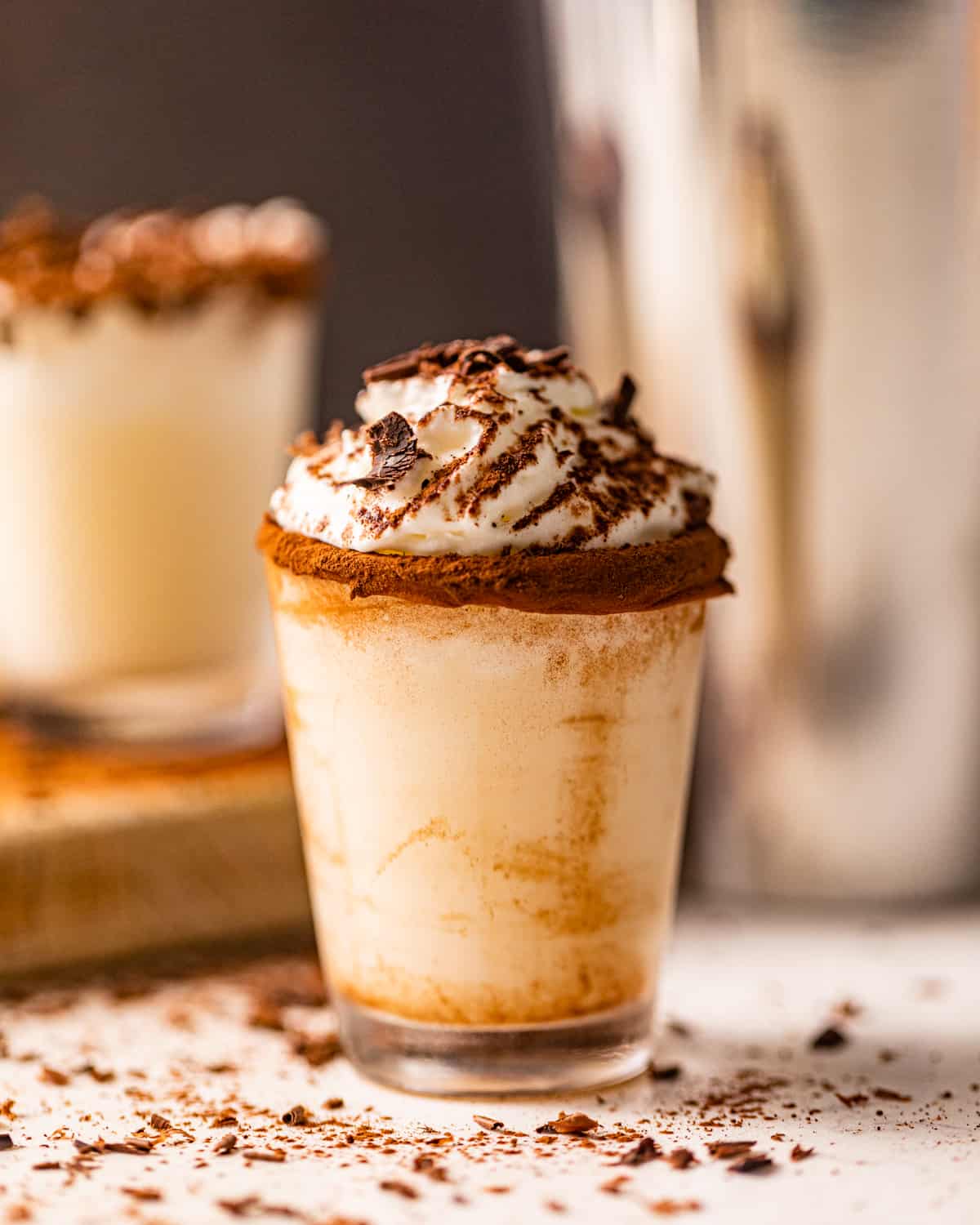 chocolate cake shot in a shot glass garnished with whipped cream and cocoa powder.