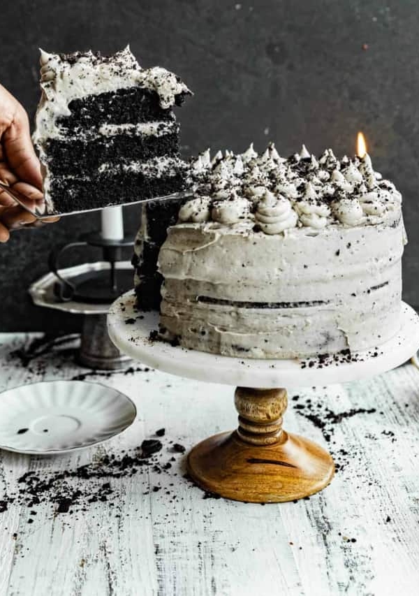 a hand lifting up a piece of cake from the black velvet cake.