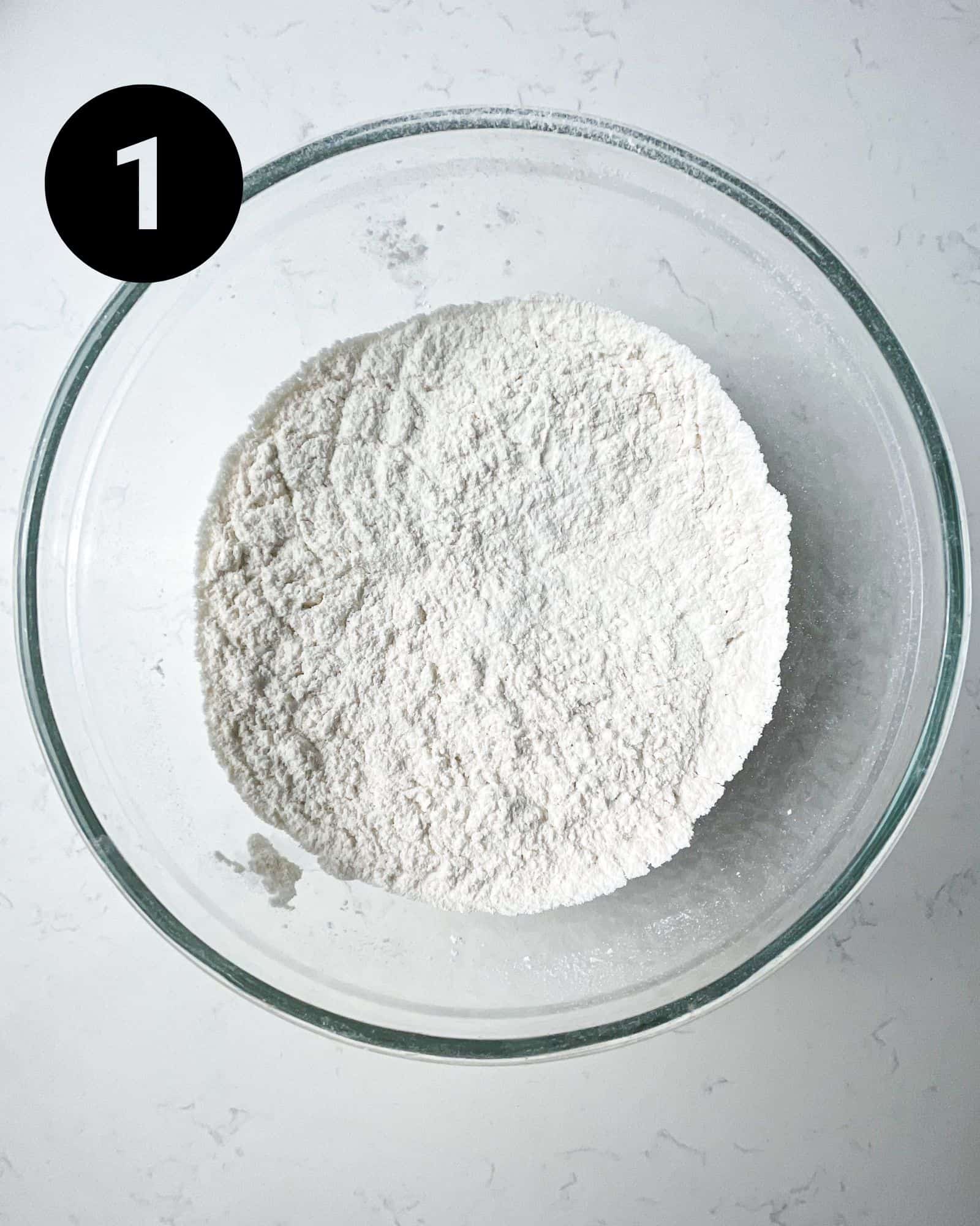 flour, baking powder, baking soda, and salt mixed together in a mixing bowl.