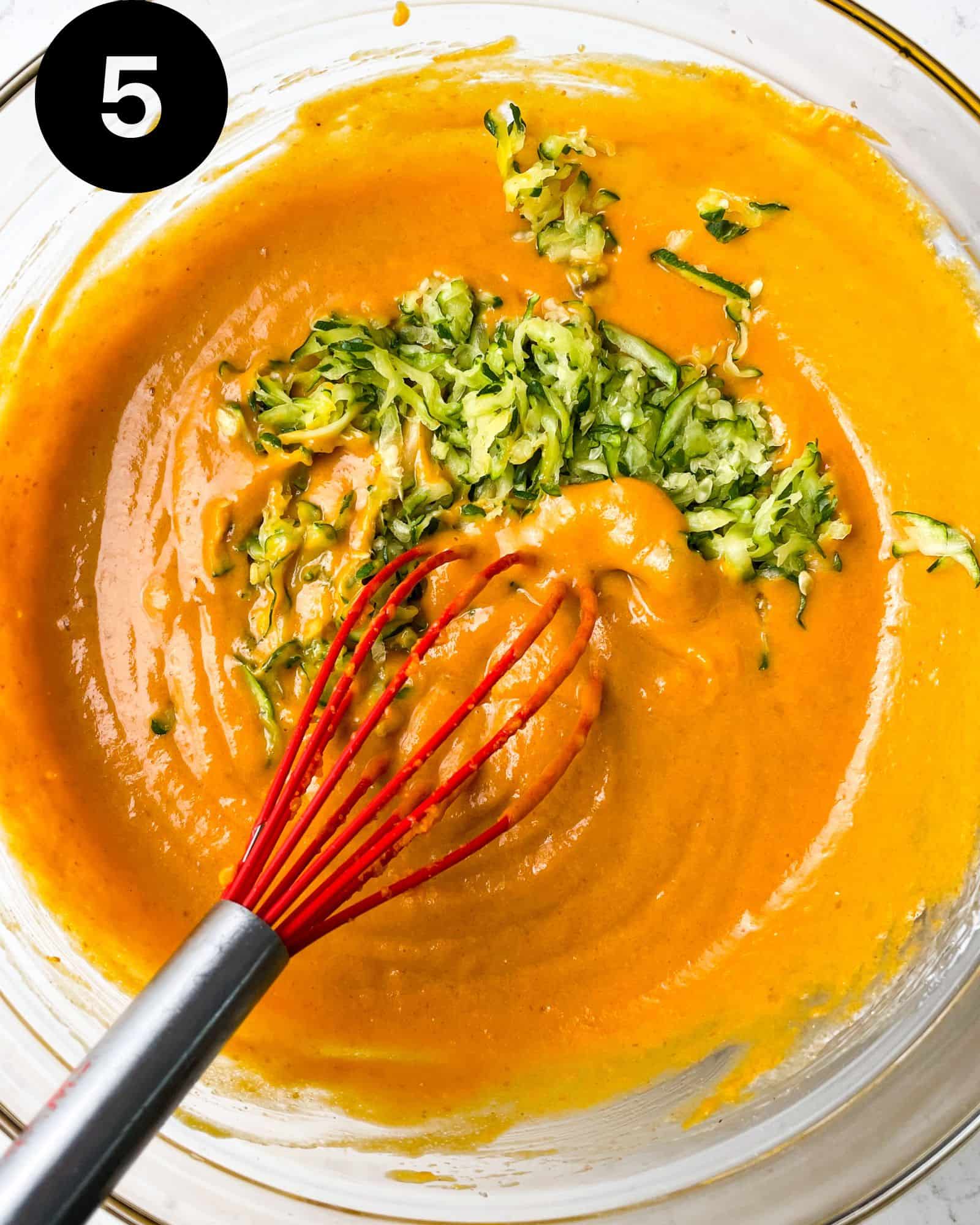 pumpkin muffin batter in a bowl with grated zucchini.