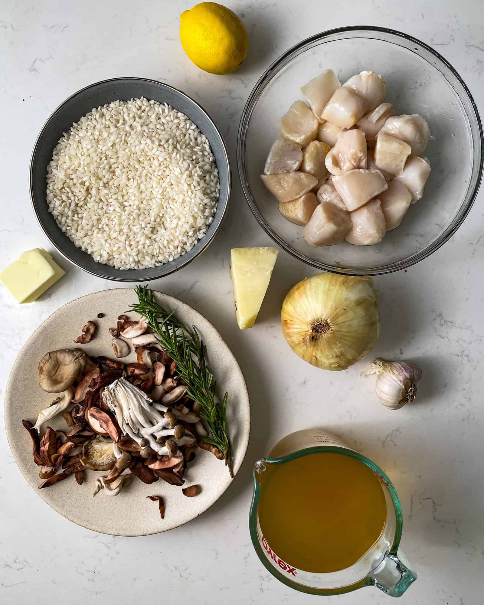 ingredients to make mushroom risotto - arborio rice, seasonings, chicken broth, dry white wine, parmesan, lemon juice and zest, mushrooms, onions, and garlic.
