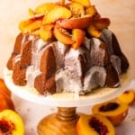 a peach cobbler pound cake on a cake stand topped with roasted peaches.
