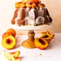 pound cake on a cake stand topped with roasted peaches.