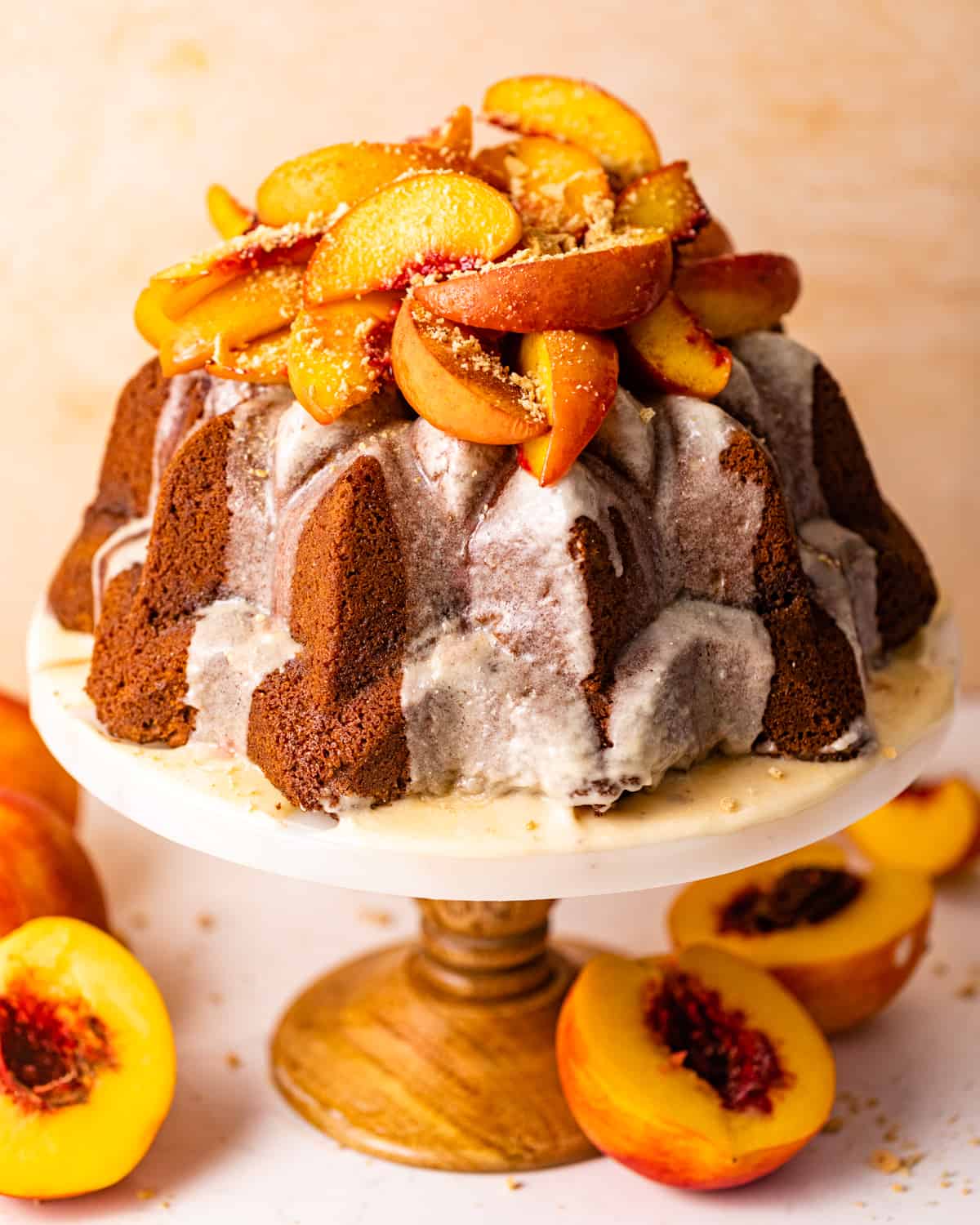 a peach cobbler pound cake on a cake stand topped with roasted peaches.