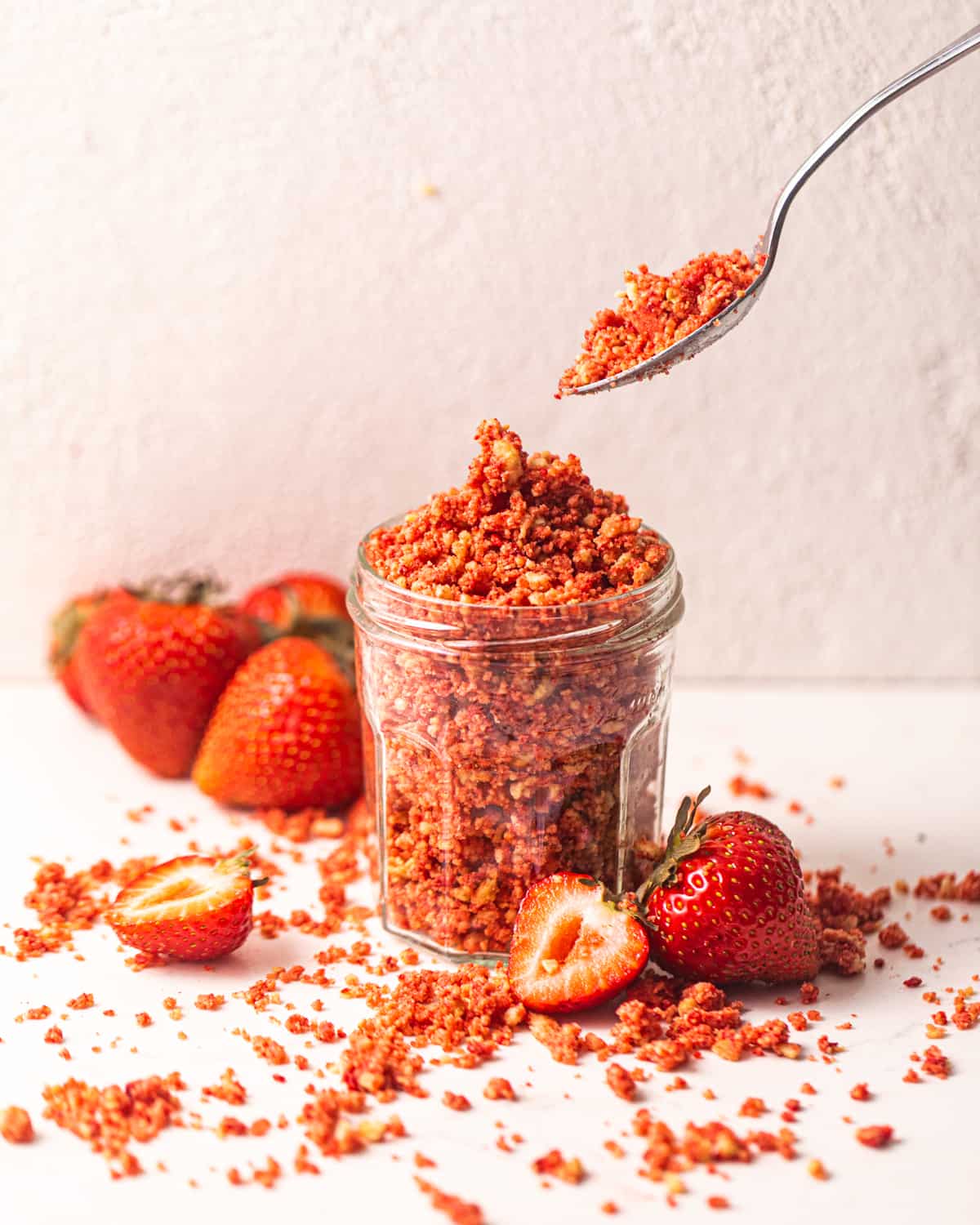strawberry crunch topping in a jar with a spoon.