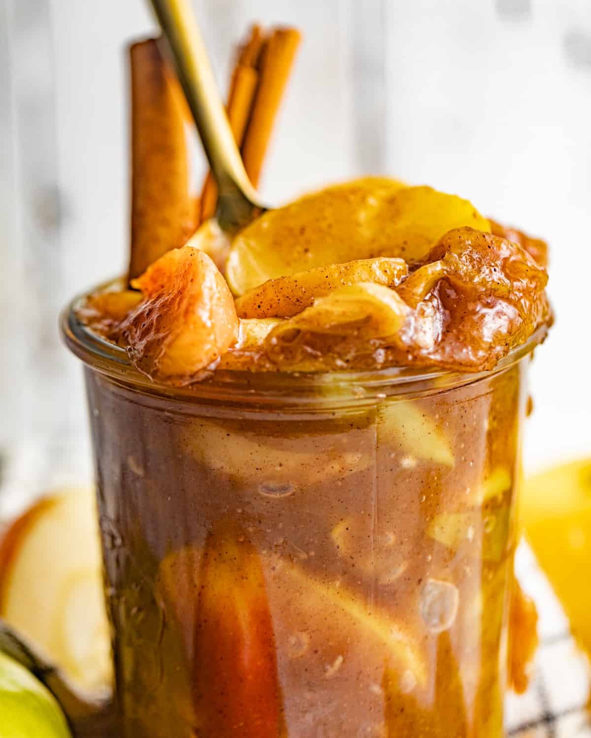 up close photo of apple pie filling in a jar with cinnamon sticks.