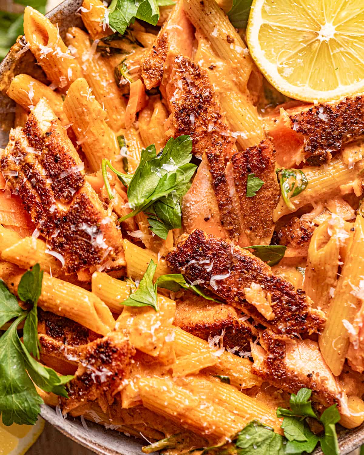 up close photo of cajun salmon pasta in a bowl garnished with fresh parsley.