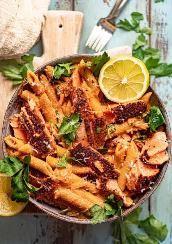 cajun salmon pasta in a bowl on top of a serving board.