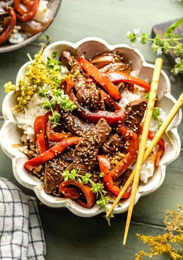 Pepper steak in a bowl with rice and bell peppers.