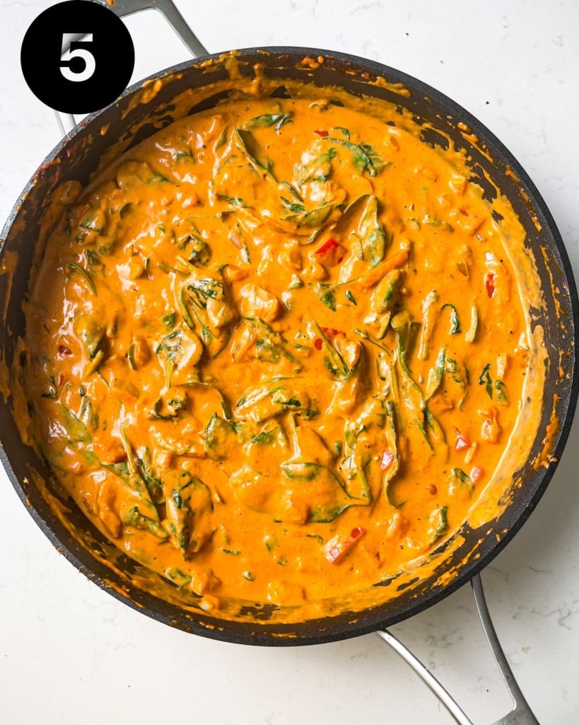 creamy cajun pasta sauce in a pan with spinach.