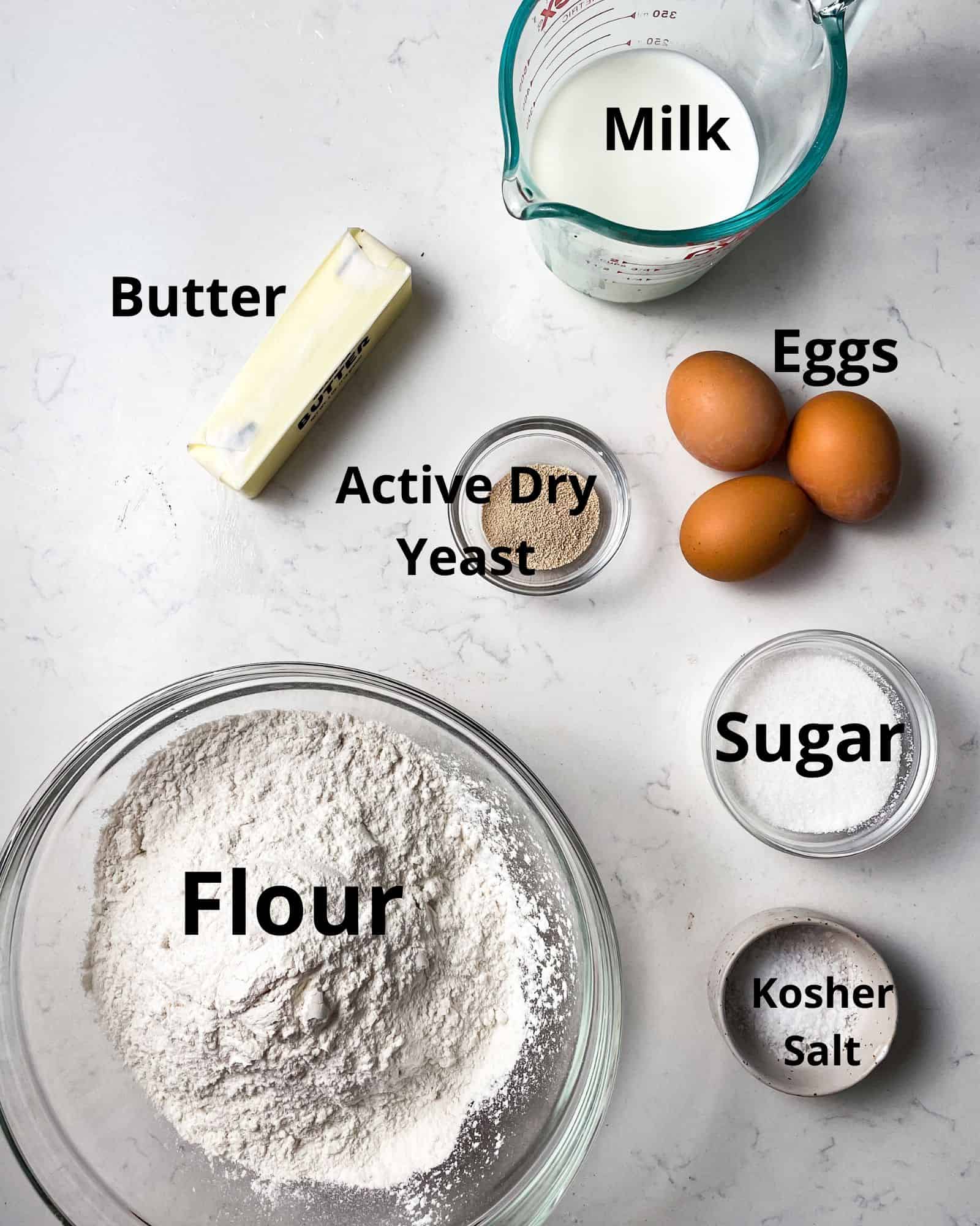ingredients to make brioche dinner rolls - flour, sugar, active dry yeast, butter, milk, and eggs.