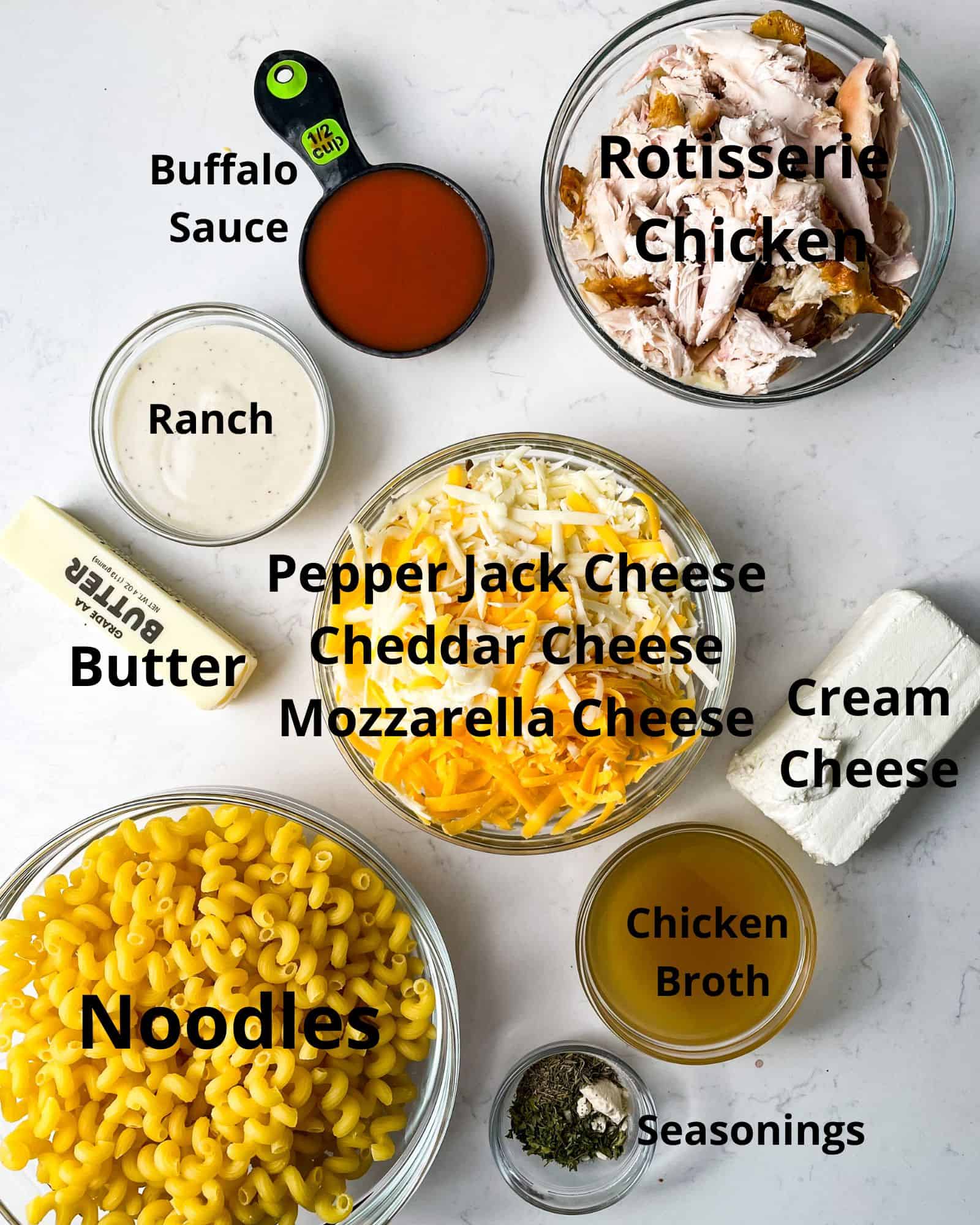ingredients to make buffalo mac and cheese - chicken, buffalo sauce, ranch dressing, cheese, seasonings, butter, and noodles.