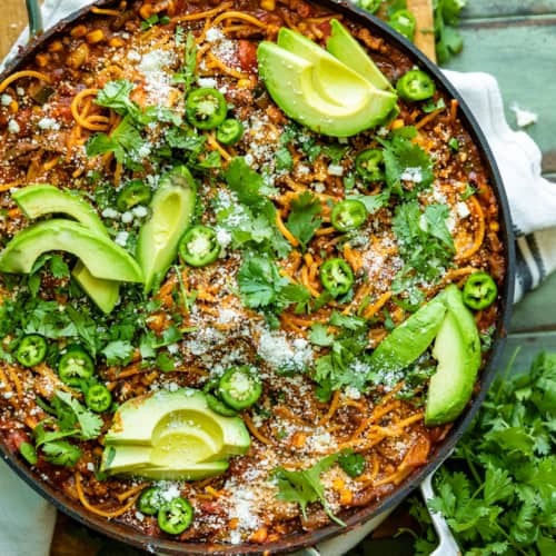 mexican spaghetti in a large skillet garnished with cotija, avocado, and cilantro.