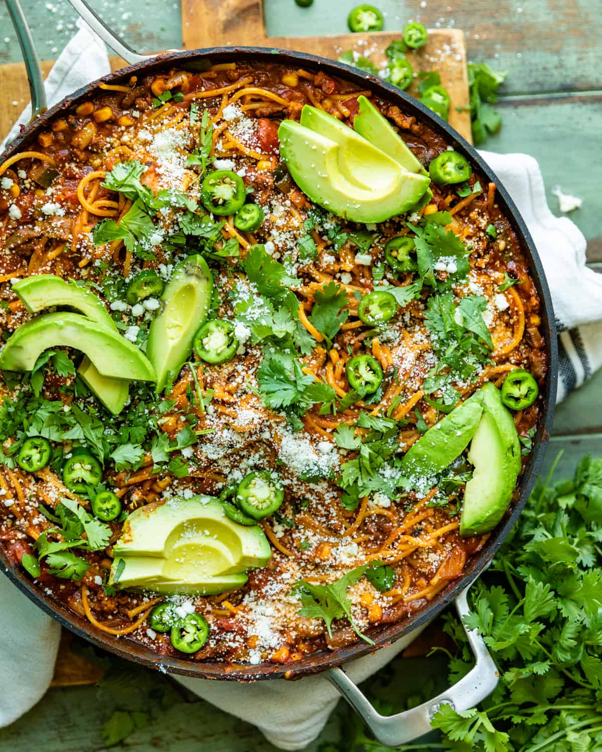 mexican spaghetti in a large skillet garnished with cotija, avocado, and cilantro.