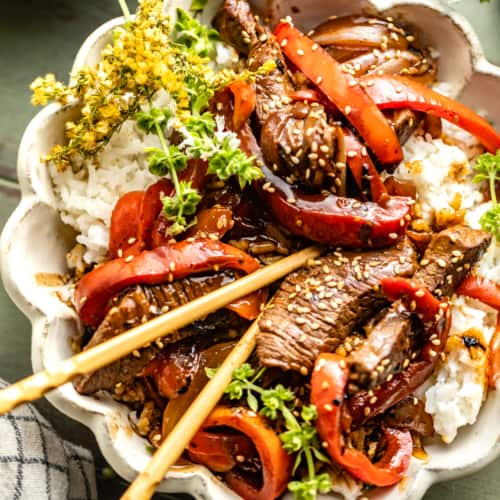 pepper steak recipe in a bowl with chopsticks.