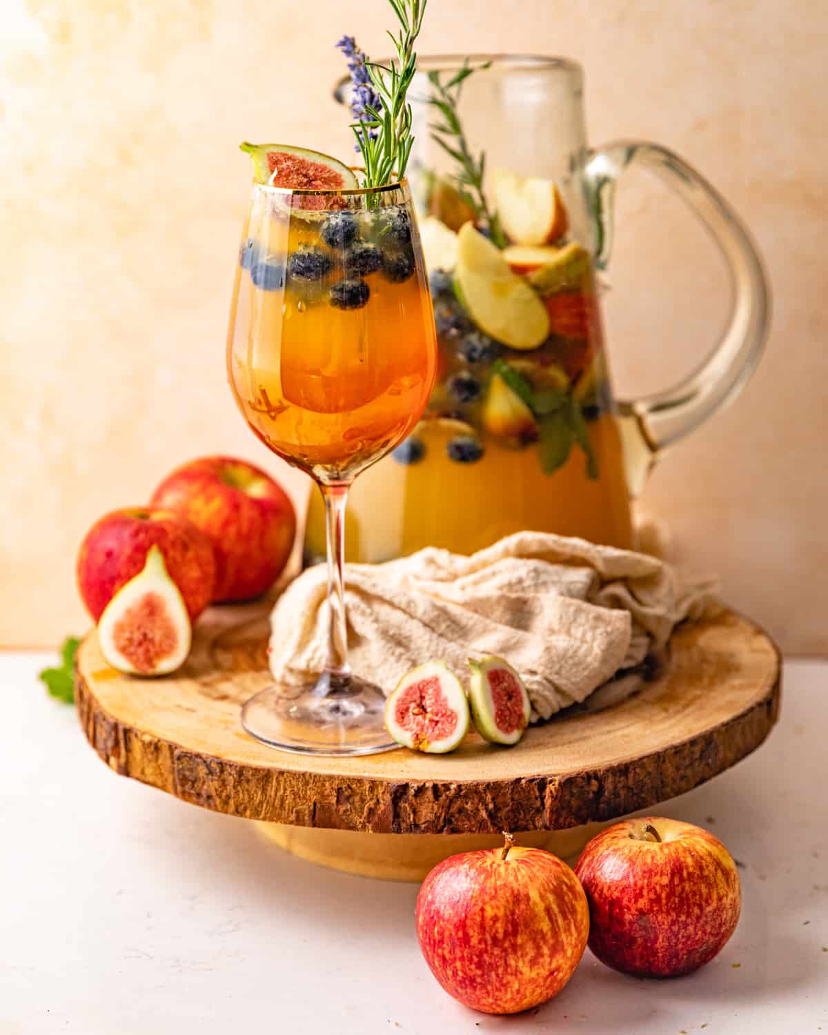 a glass of white wine sangria in front of a large pitcher.
