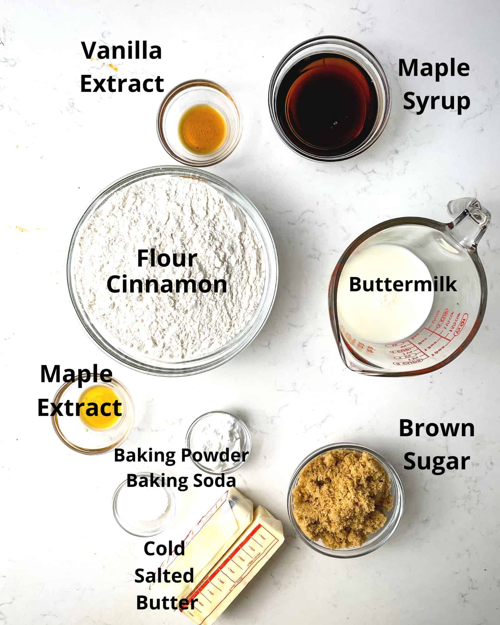 ingredients to make maple biscuits - flour, brown sugar, buttermilk, maple syrup, vanilla extract, maple extract, salted butter, baking powder, baking soda, and salt.