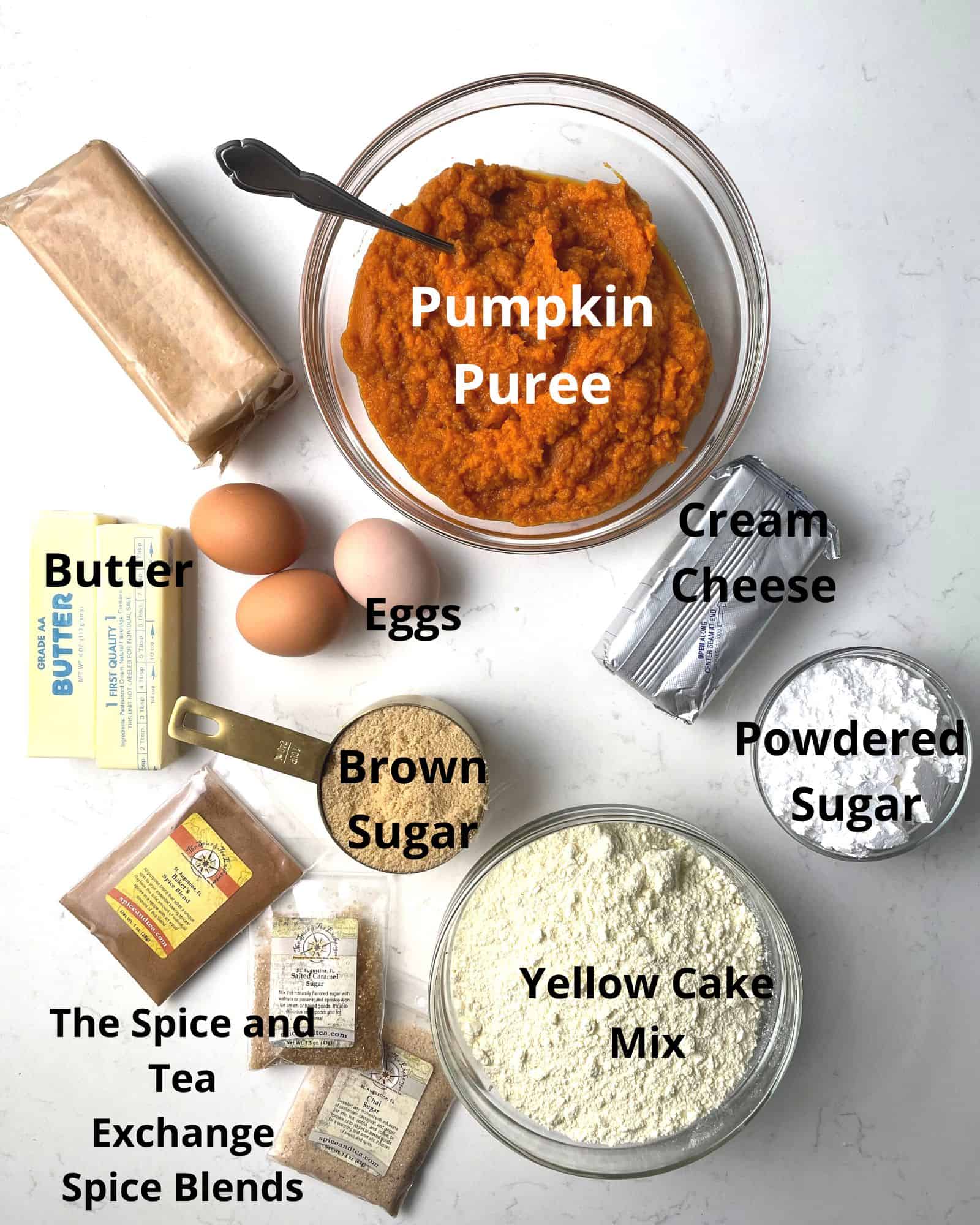 ingredients to make pumpkin cream cheese dump cake - pumpkin puree, cream cheese, powdered sugar, butter, brown sugar, eggs, yellow cake mix, and spices.