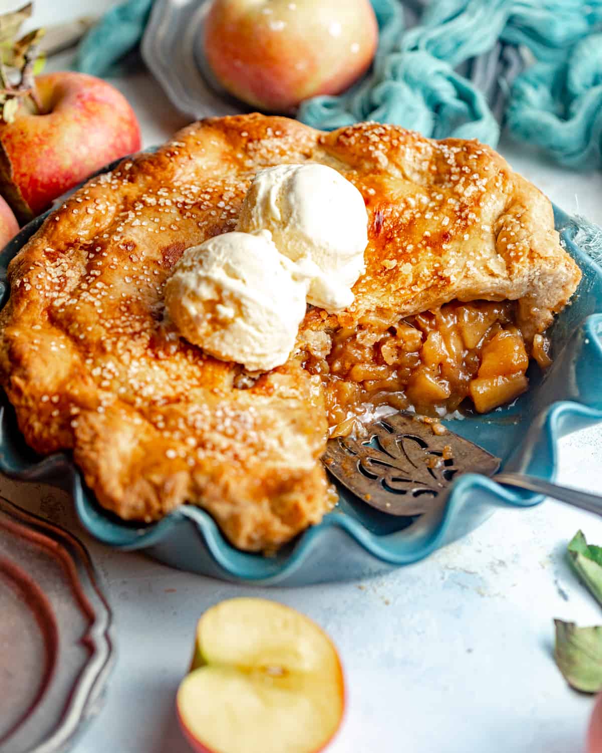 sliced apple pie in a pie plate with ice cream on top.