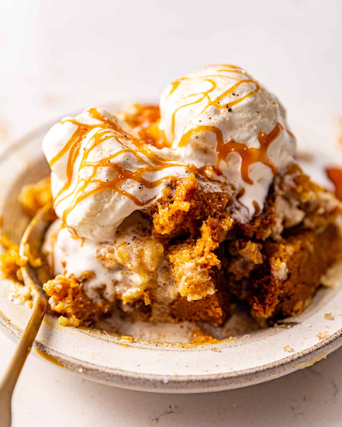 pumpkin cream cheese dump cake in a bowl topped with ice cream.