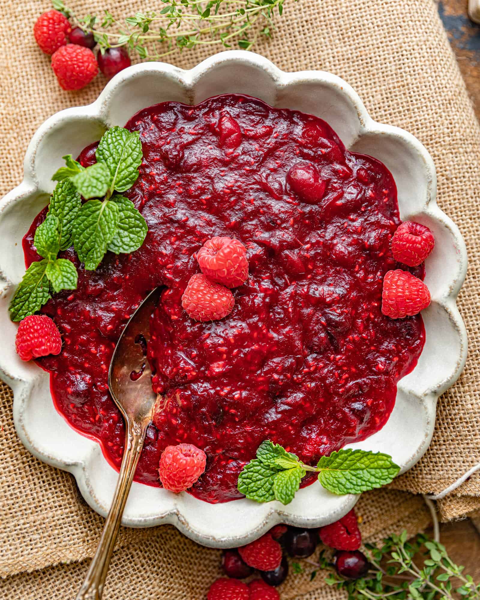 cranberry raspberry sauce in a bowl topped with fresh raspberries.