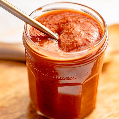 honey bbq sauce in a jar with a spoon.