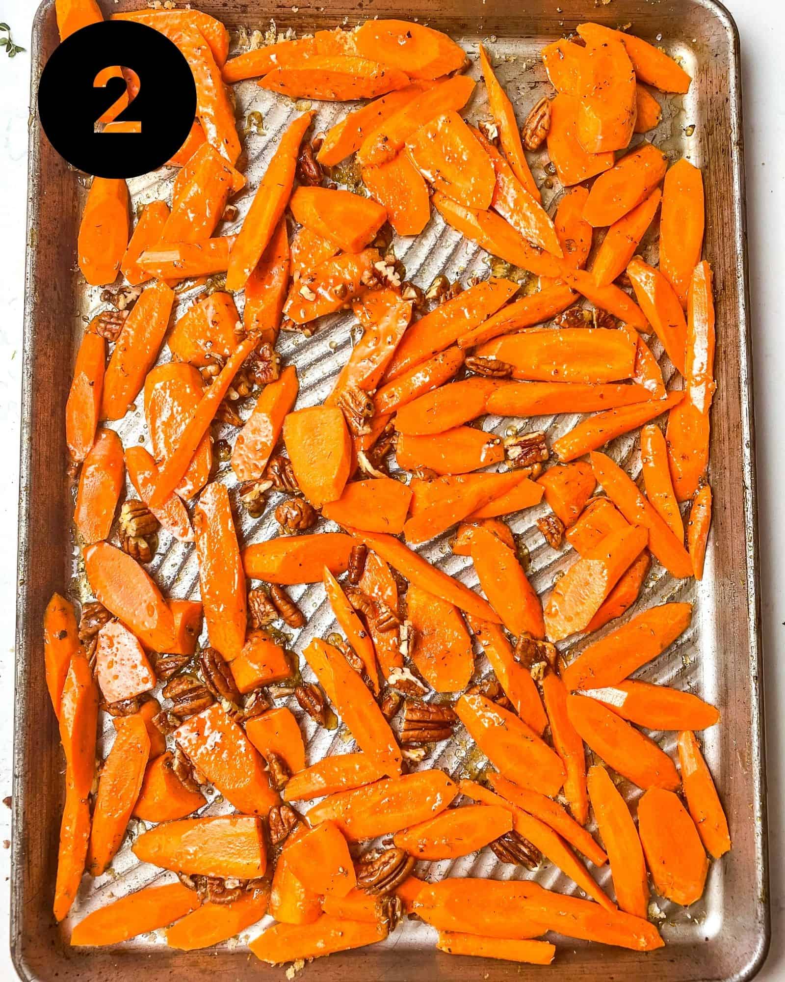 sliced carrots on a baking sheet with brown sugar, honey, thyme, and pecans.
