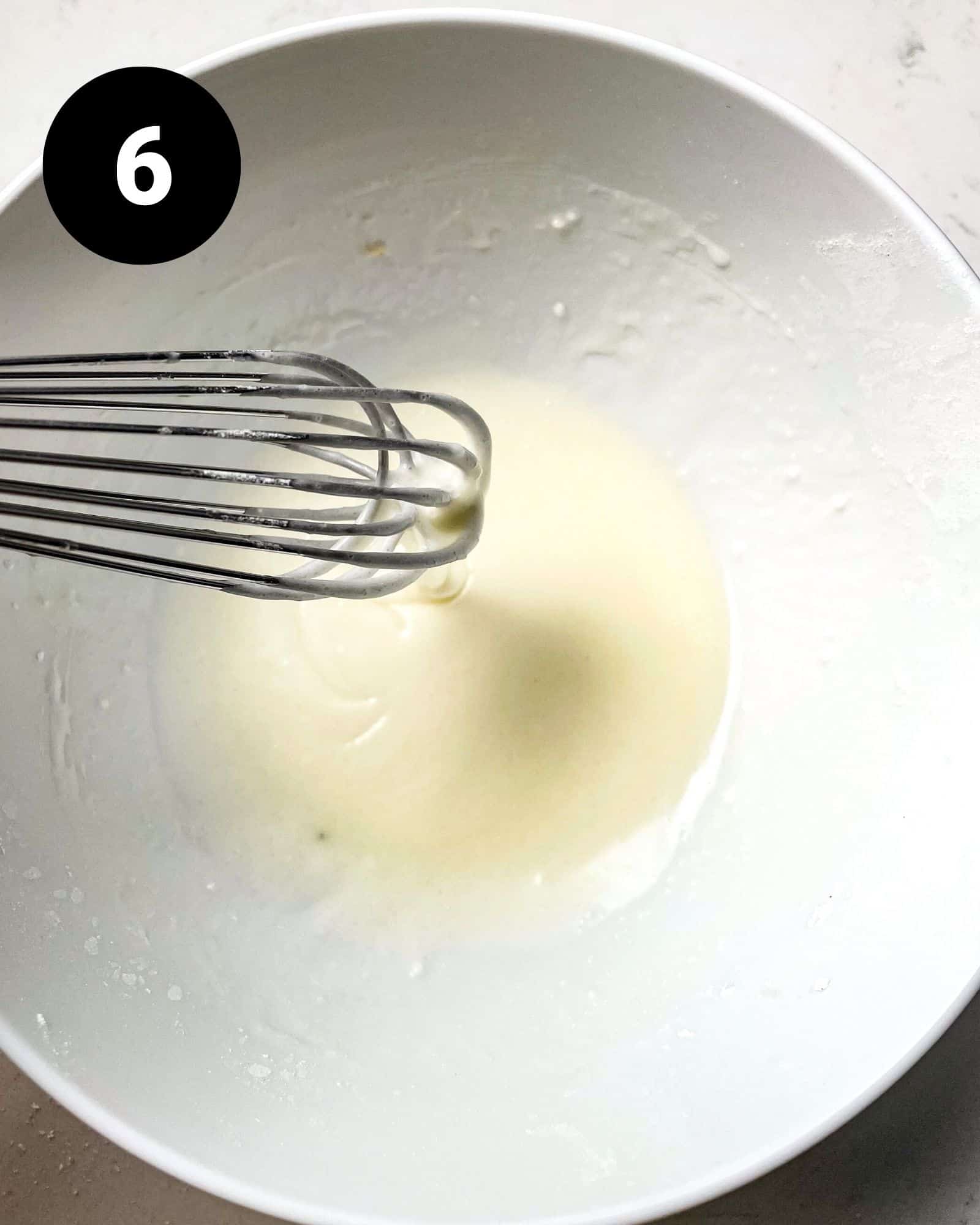 lemon glaze in a bowl with a whisk.