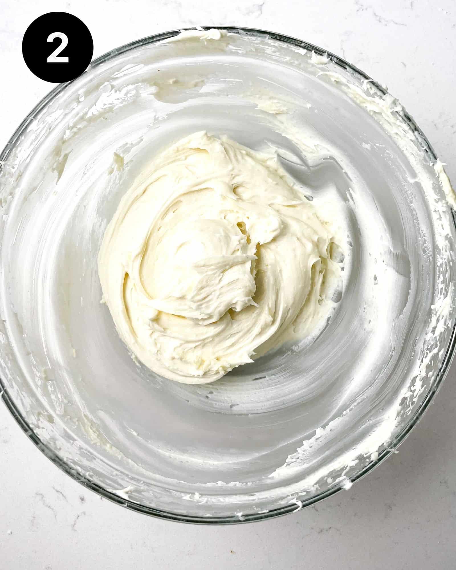 cream cheese and white chocolate whisked together in a bowl.