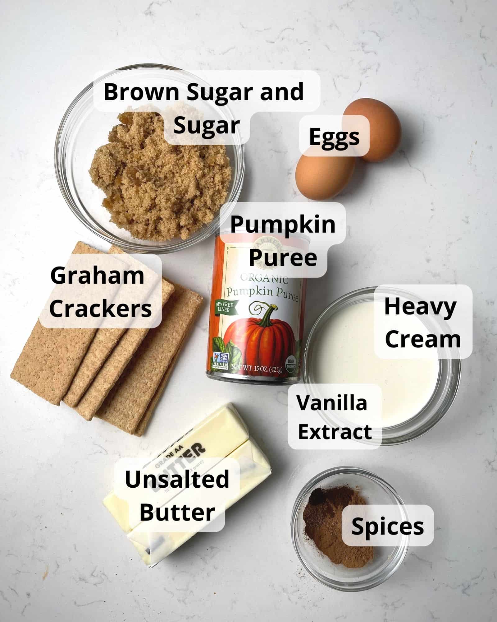 ingredients to make pumpkin pie with graham cracker crust - brown sugar, sugar, eggs, pumpkin puree, heavy cream, vanilla extract, unsalted butter, spices, and graham crackers.