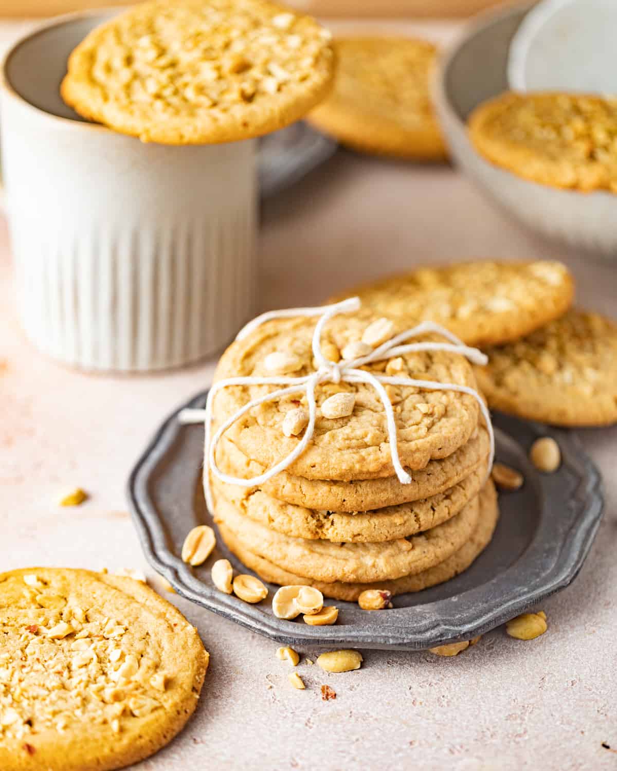 chewy peanut butter cookies on a silver plate wrapped with a bow.