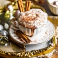 a cup of crock pot hot chocolate in a cup with cinnamon sticks and topped with whipped cream.