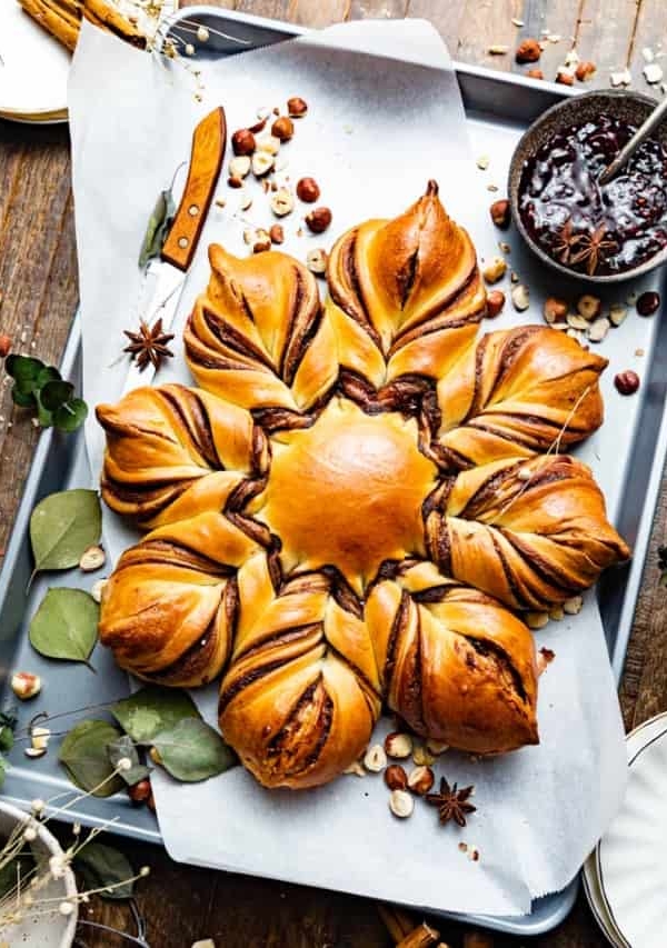 chocolate starbread on a baking sheet next to a bowl of raspberry preserves.