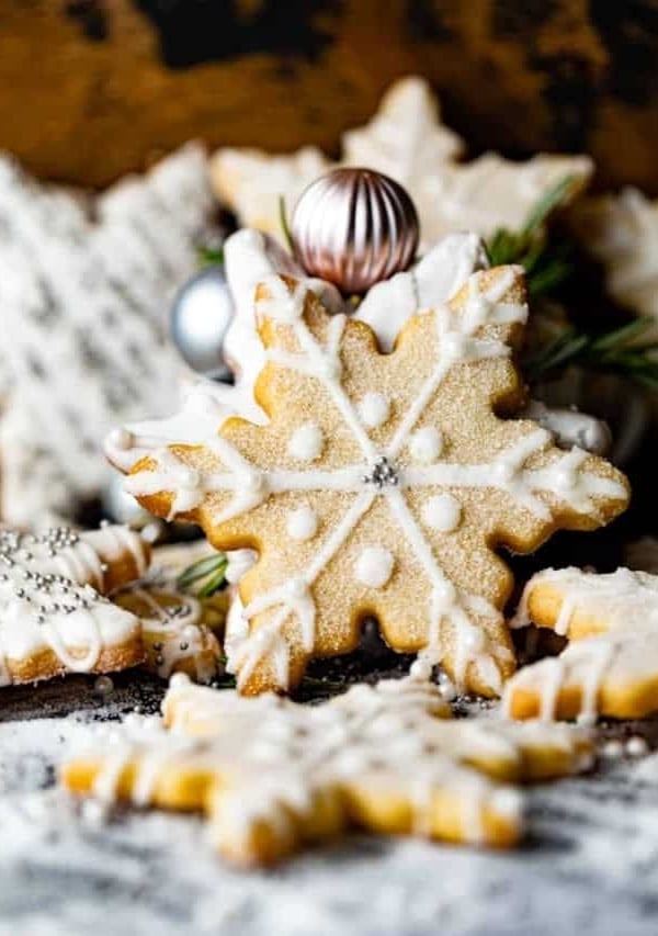 a stack of snowflake cookies placed on a table with a tea cup.