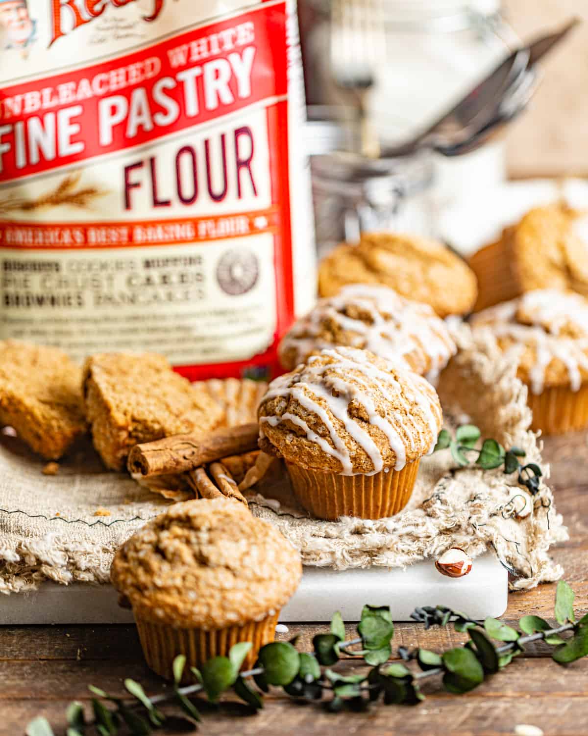 a gingerbread muffin on a wood table in front of a bag of pastry flour.