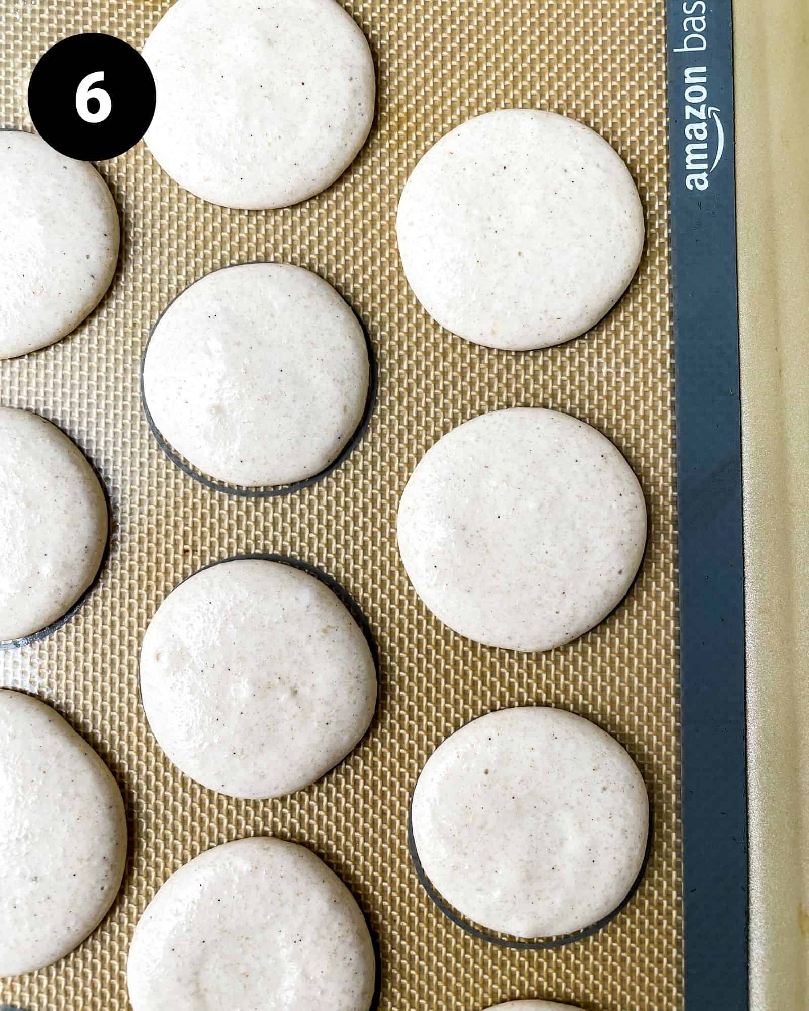 gingerbread macaron shells on a silicone baking mat.