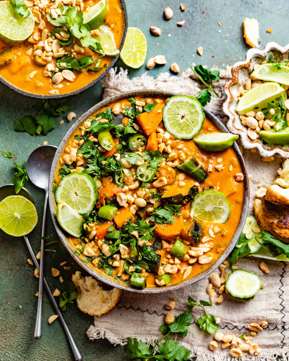 peanut butter soup in a bowl garnished with limes, peanuts, and cilantro.