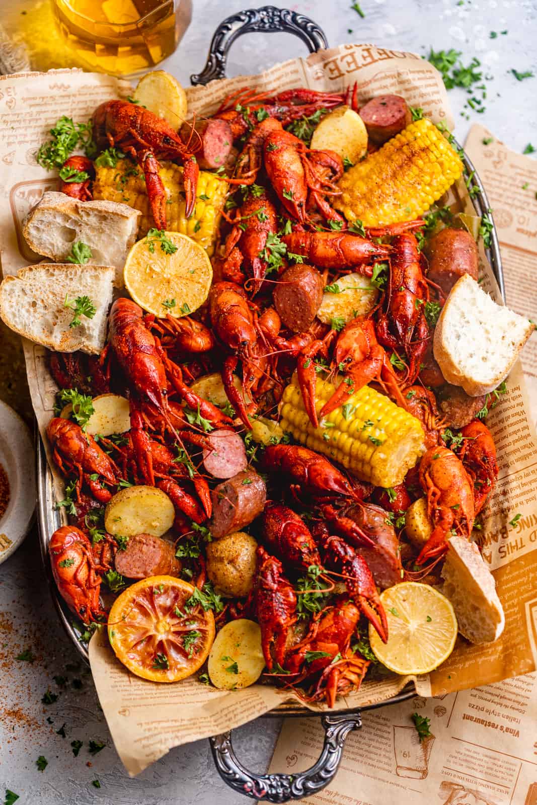 boiled crawfish on a serving dish with fresh bread, corn, potatoes, and sausage.