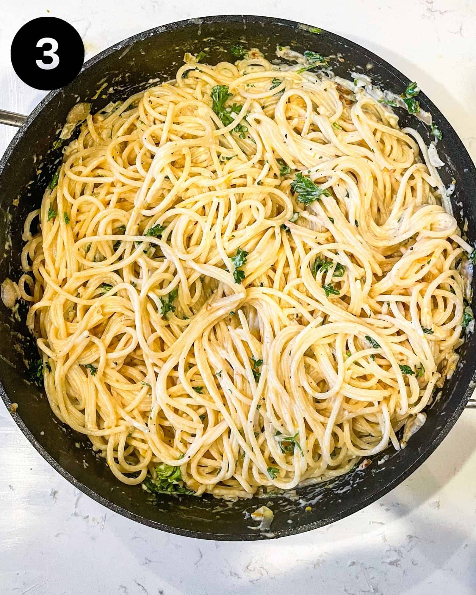 spaghetti noodles added to a large skillet with lemon garlic sauce.