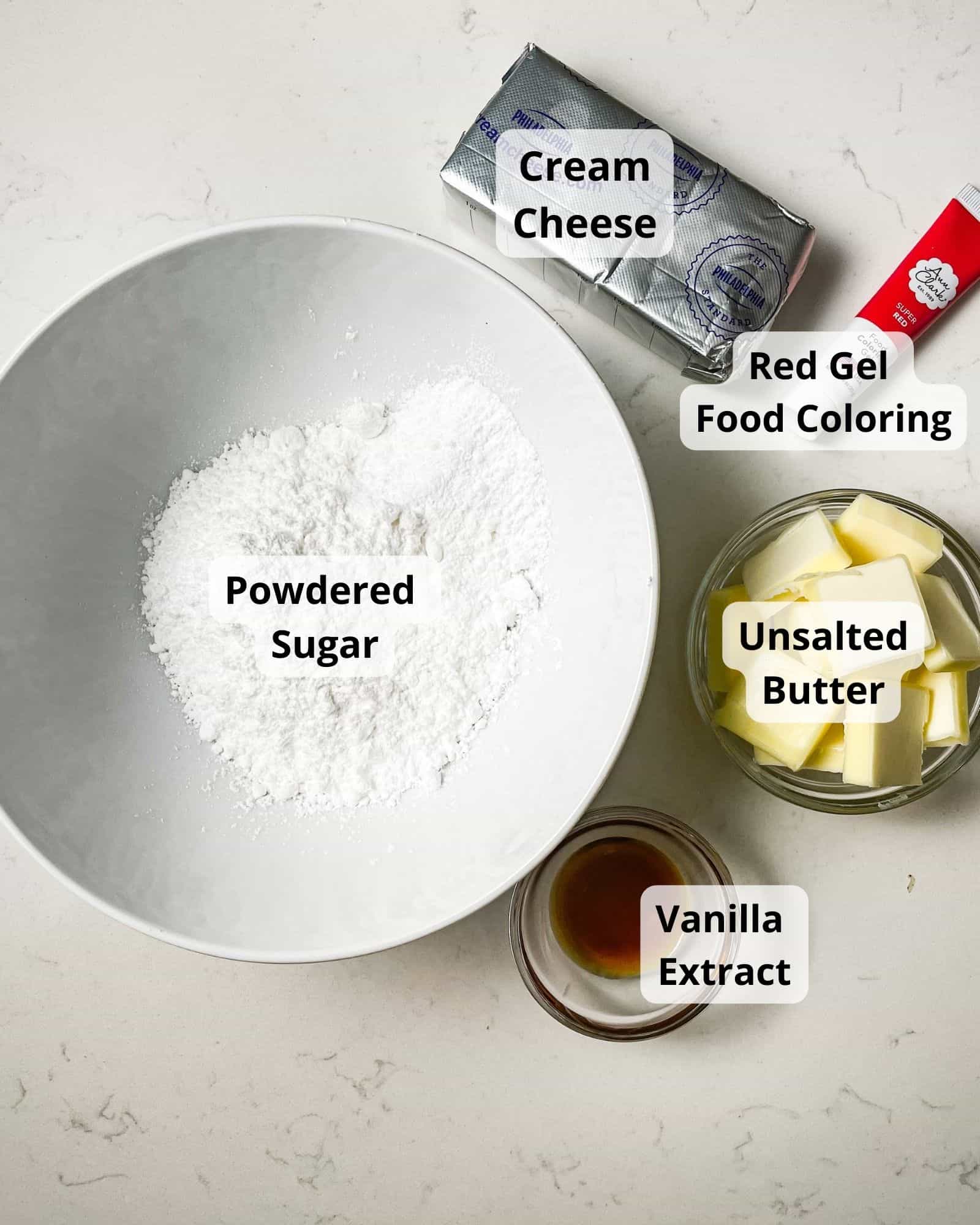 ingredients to make cream cheese frosting - powdered sugar, cream cheese, butter, red food coloring, and vanilla extract.