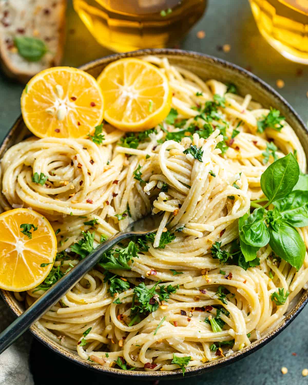 lemon garlic pasta in a bowl with a fork and sliced lemons on top.