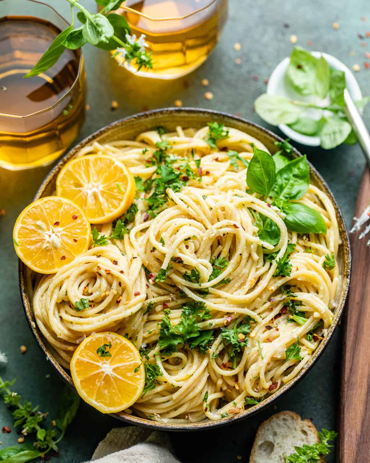lemon garlic pasta in a bowl with sliced lemons and fresh basil on top.
