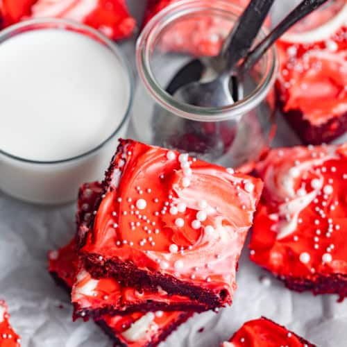 red velvet brownies on a serving platter cut into square pieces next to a glass of milk.