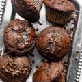 double chocolate chip muffins on a silver tray garnished with chocolate chips and flaky salt.