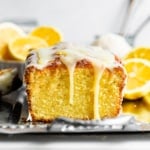 a lemon loaf on a serving tray with lemon glaze dripping down.