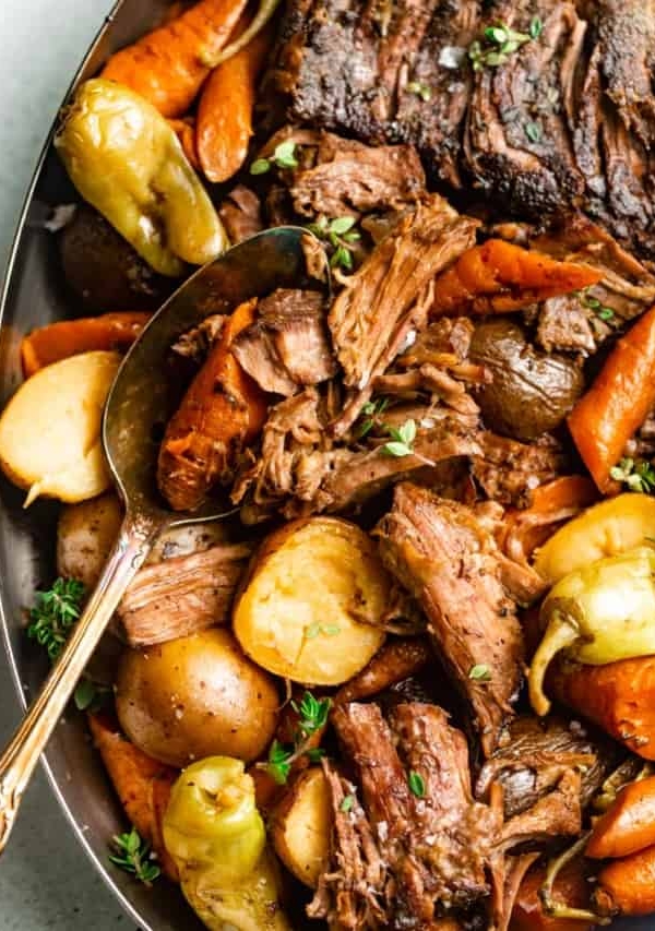 Mississippi Pot Roast in a serving dish with potatoes and carrots.