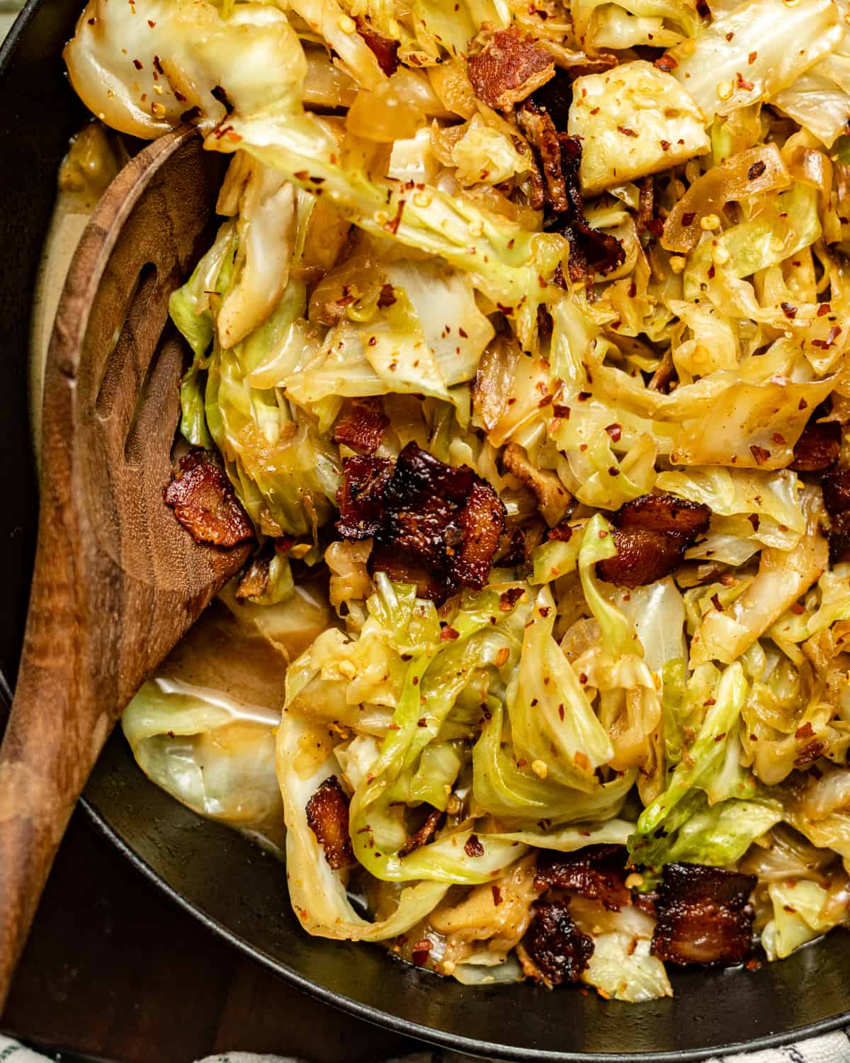 fried cabbage in a skillet with wooden spoon.
