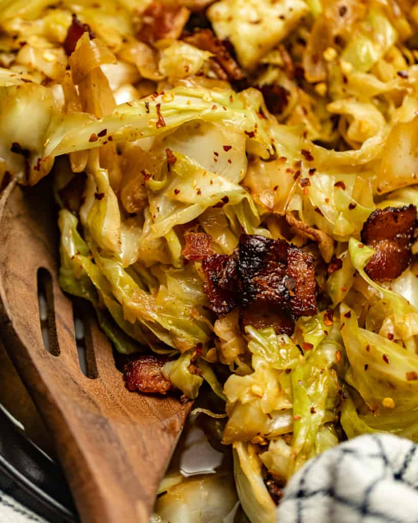 up close photo of fried cabbage on a spoon with bacon bits.